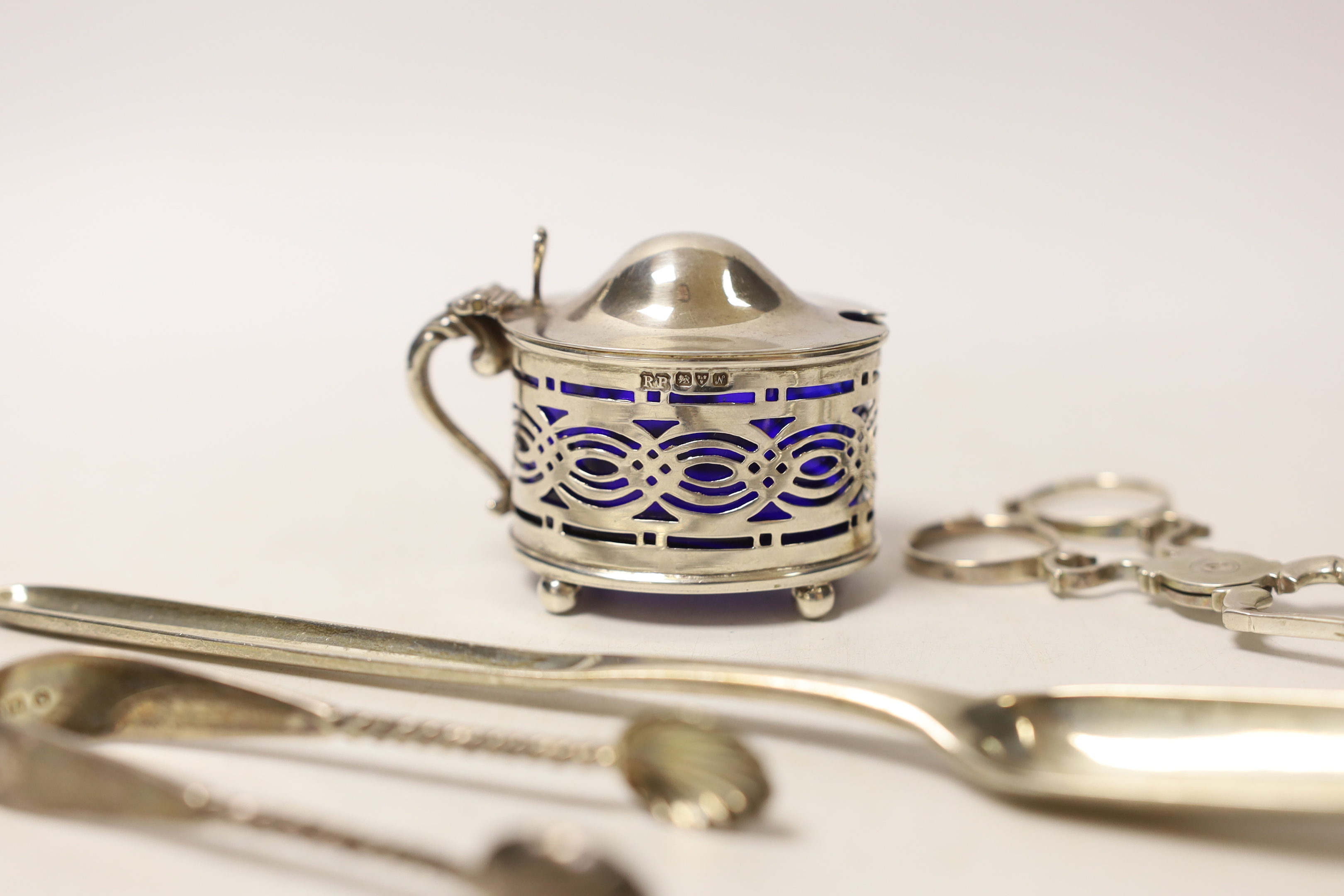 A George III silver marrow scoop, Stephen Adam, London, 1772, 21.5cm, a pair of mid to late 18th century silver sugar nips, a later silver mustard and pair of silver sugar tongs.